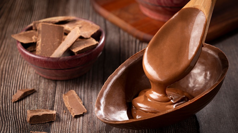 chocolate ganache being poured with a wooden spoon