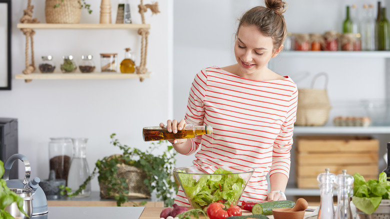 Woman adding oil to a vegetable salad