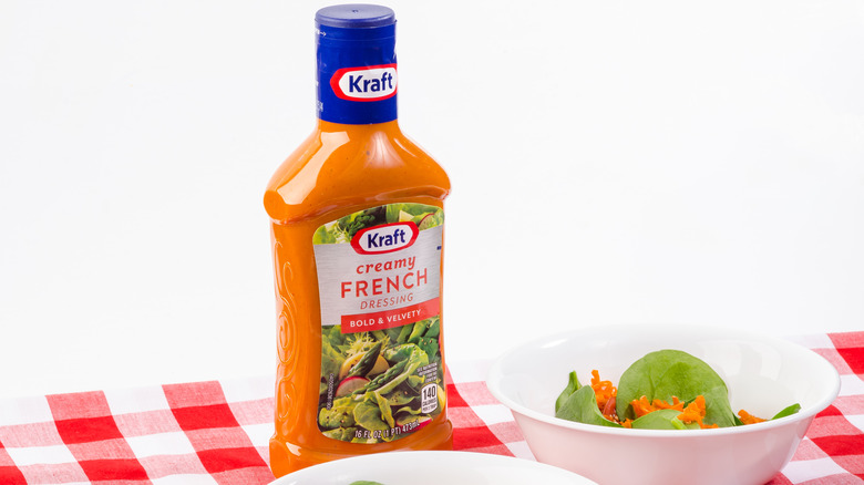 Bottle of Kraft creamy French dressing beside small salads