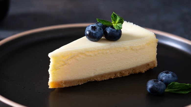 Slice of vanilla cheesecake on dark plate