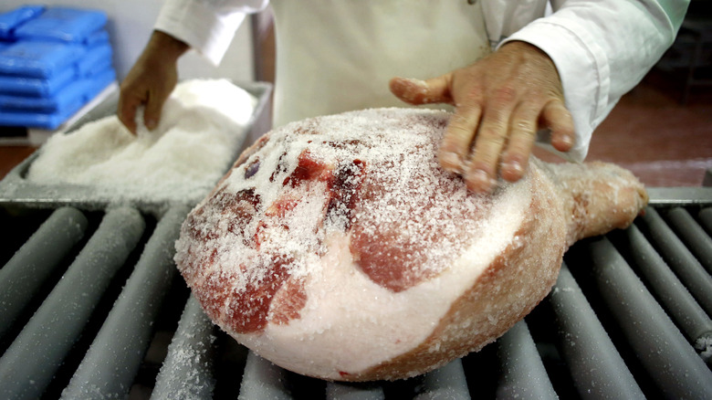 Person applying salt to ham 