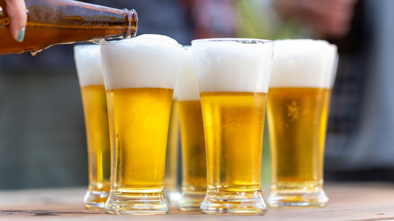 Hand pouring beer into glasses.