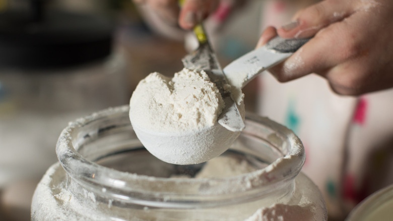 Hand measuring a cup of flour