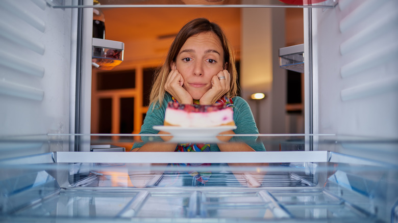 woman watching cheesecake in refrigerator