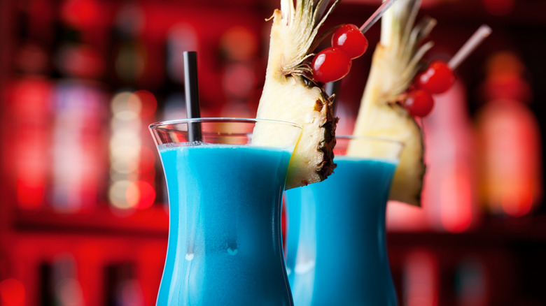 two blue hawaiian cocktails on a bar