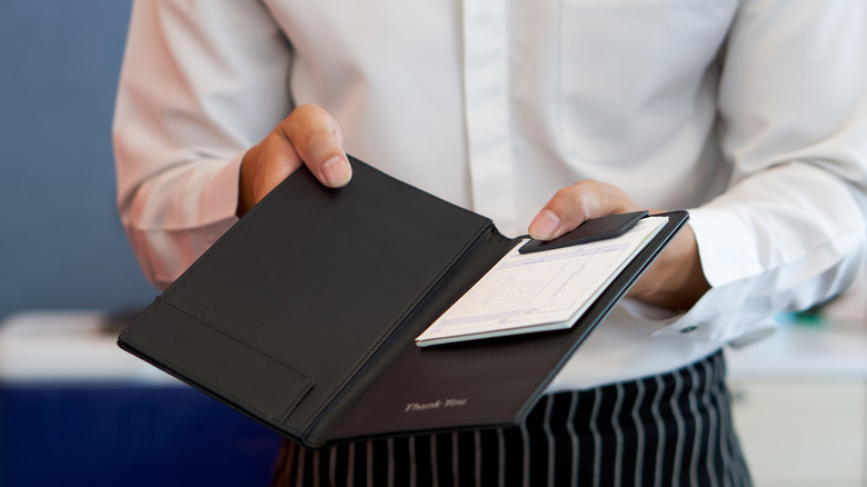 Waiter holding restaurant check book