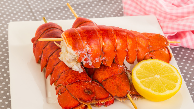 Skewered lobster tails with lemon on plate