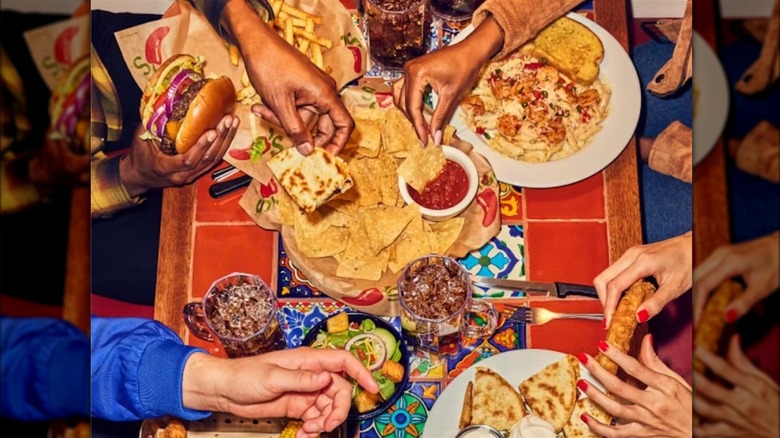 table full of hands grabbing food at chili's