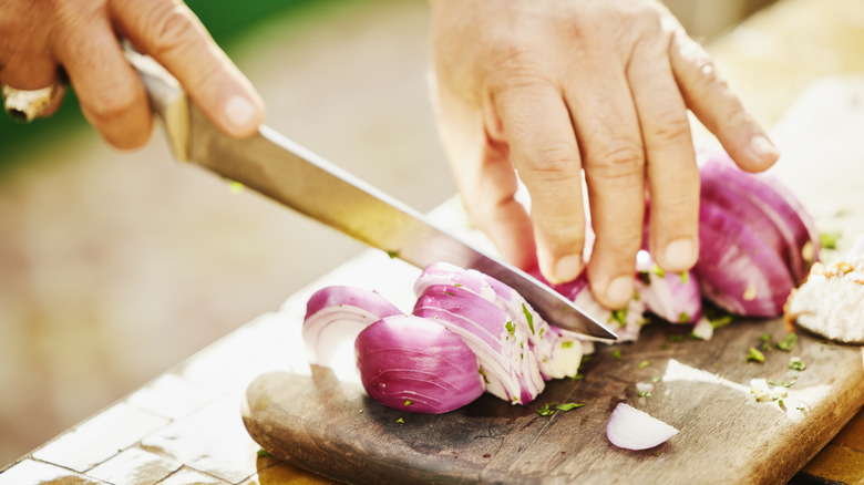 man chopping onion on wooden cutting board