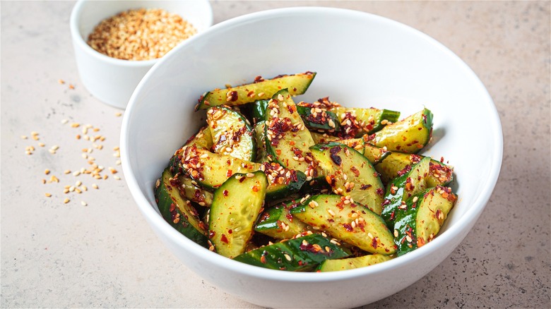 Smashed cucumber salad with chili in bowl on counter