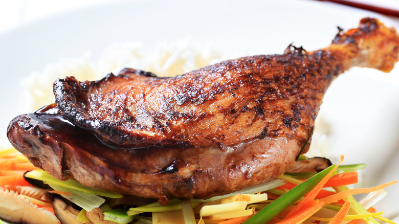 crispy duck leg on a bed of vegetables