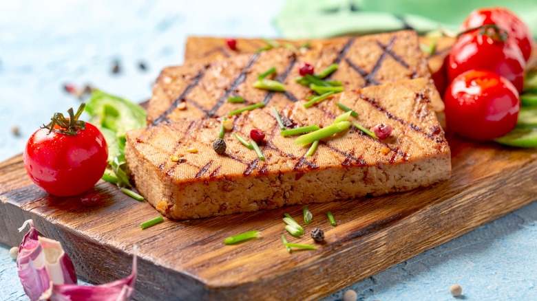 Grilled tofu steaks on wooden board.