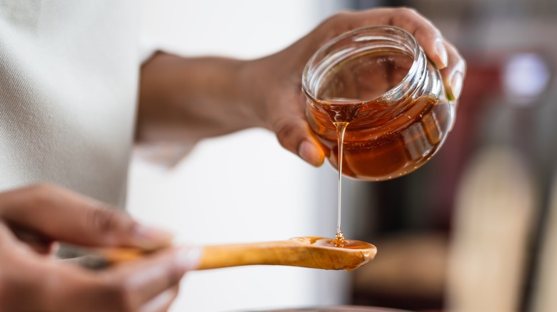 person holding honey and spoon