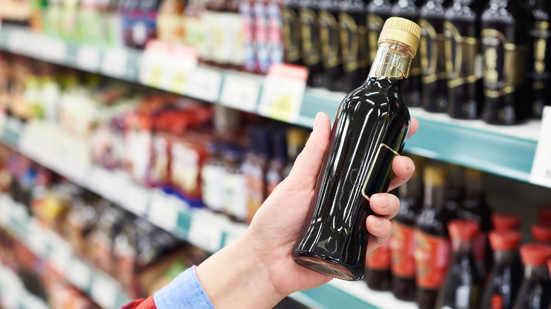 Man holding a bottle of dark soy sauce in a store