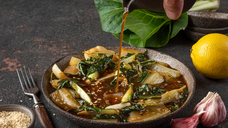 Man adding soy sauce to bok choy 