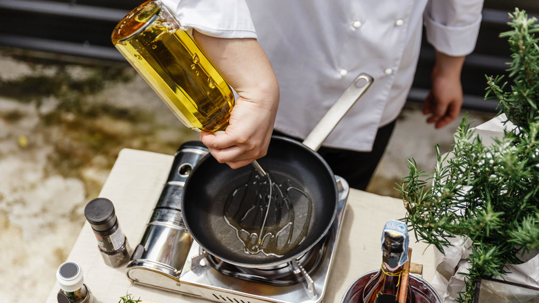 A chef pours oil onto a pan