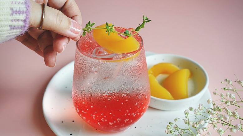 A person adds a garnish to a fizzy drink