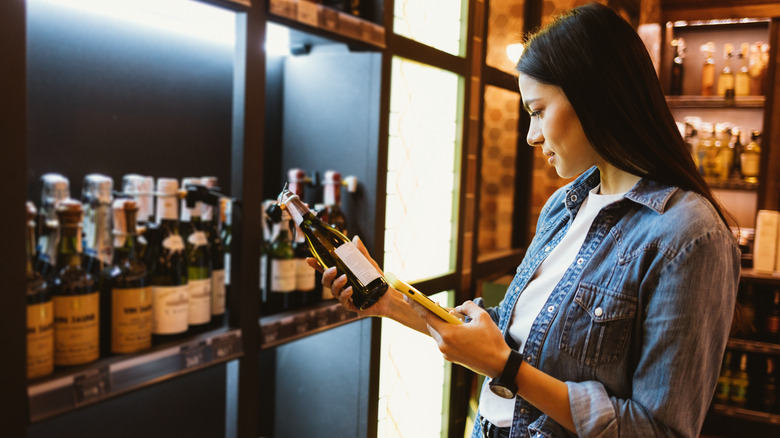 woman staring at label on a bottle of wine