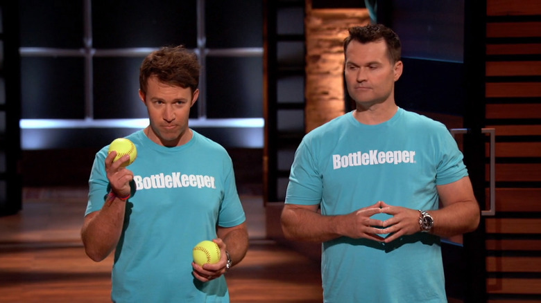 Adam Callinan holds two baseballs while standing next to Mark Campbell