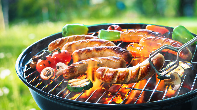 cooking sausages and vegetables on a charcoal grill