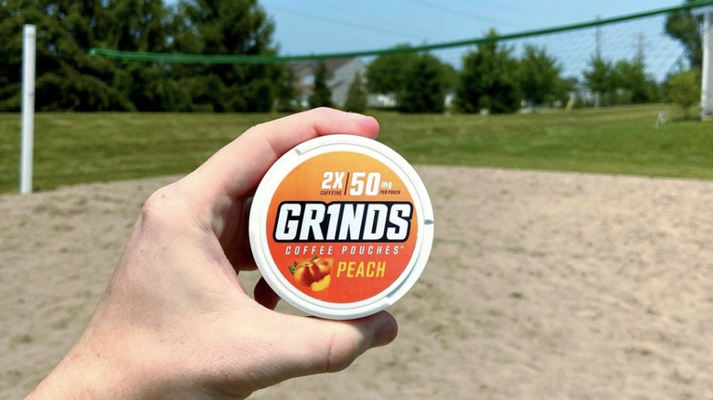 Person holding Grinds container