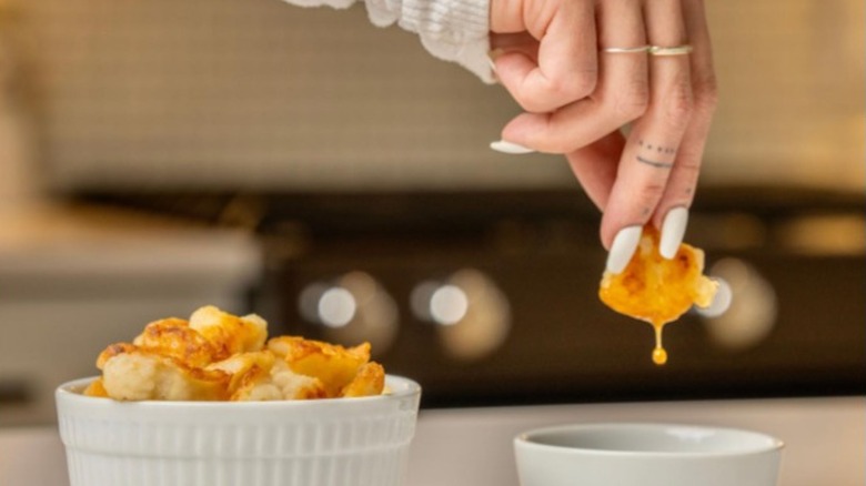 Person dipping cauliflower wings into sauce