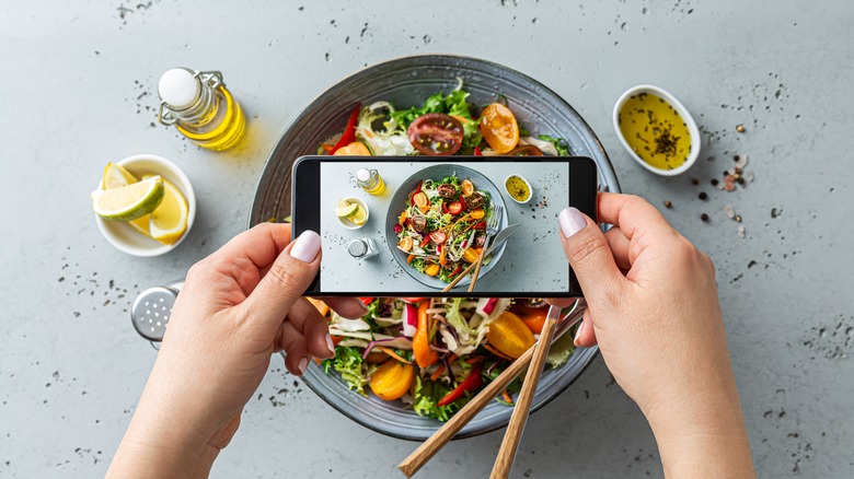 person taking picture of food with phone