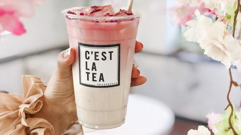 woman's hand holding pink Teaspressa tea latte