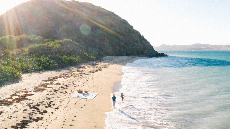 Two people walk along a beach