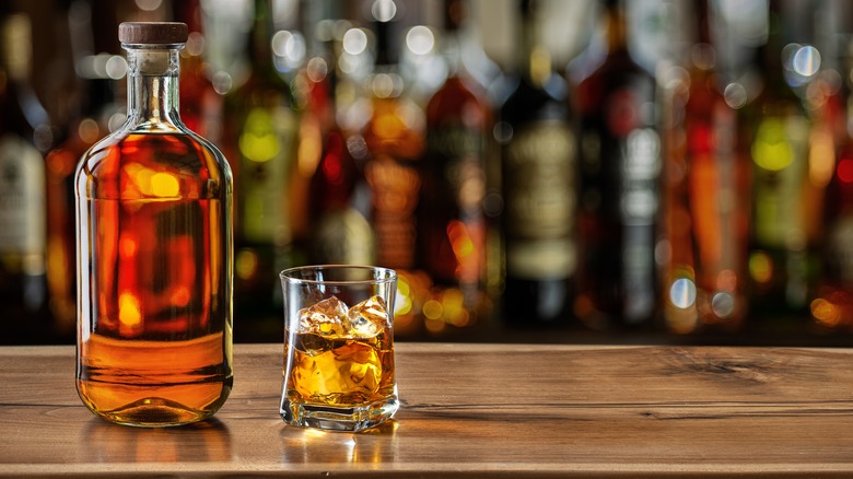 bottle of liquor and small glass sit on a bar