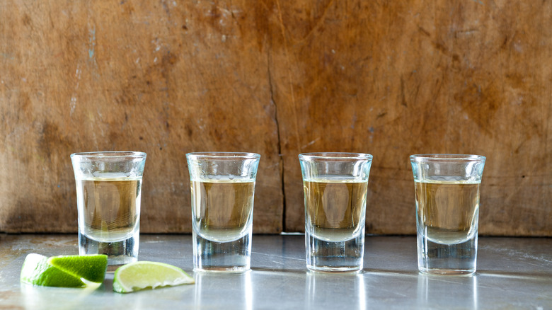 Shot glasses on a table with lime wedges