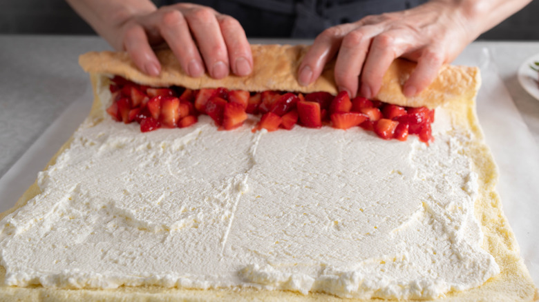 rolling cake with frosting and fruit