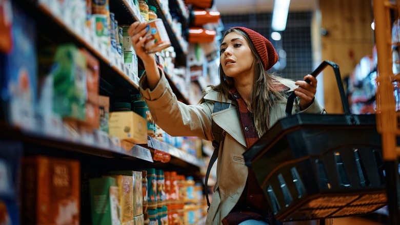 woman reading product label in grocery store