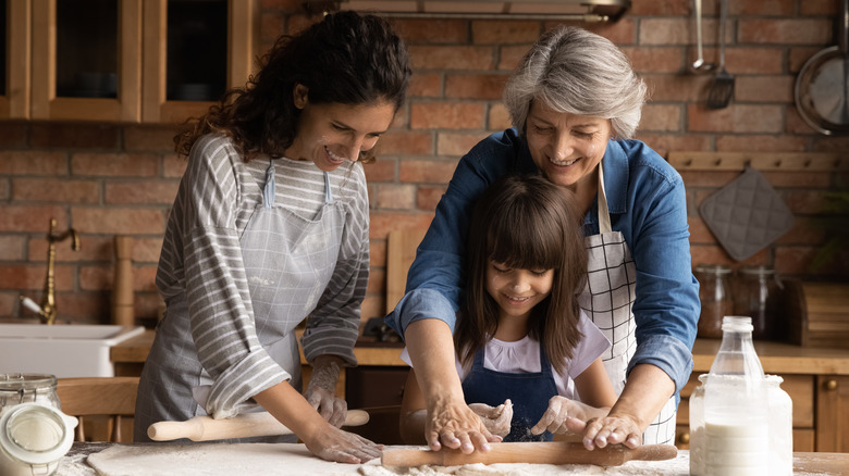 three female family members of various ages rolling out baking dough