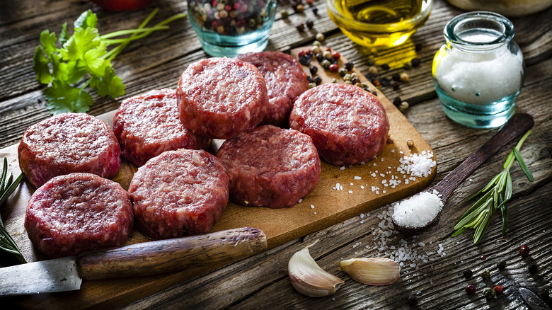 raw burger patties on cutting board