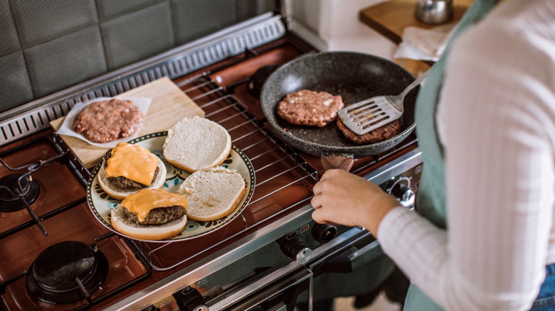 woman frying burgers in a pan