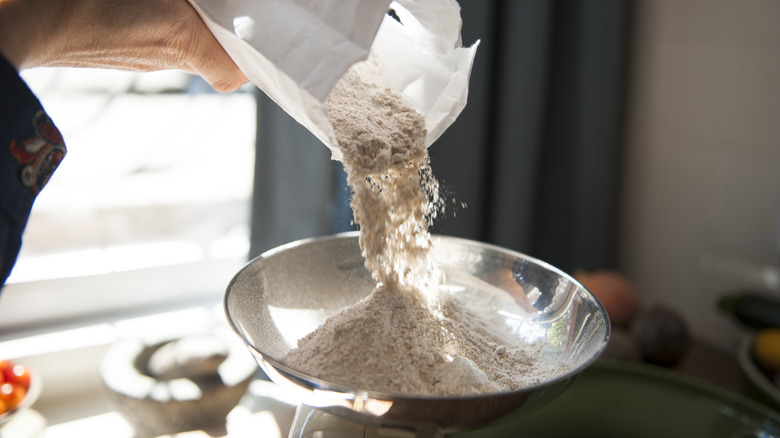 person weighing flour on scale