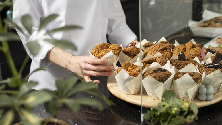 baker serving bakery muffins