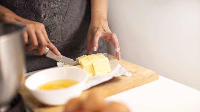 women in apron cutting butter