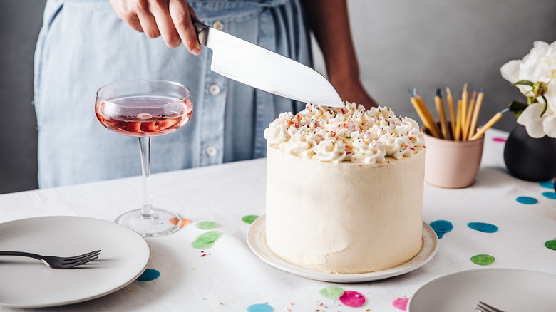 Baker cutting into birthday cake with rainbow sprinkles