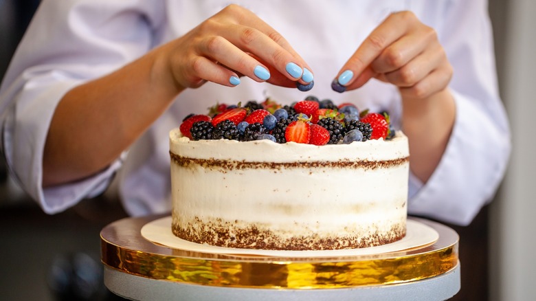 baker decorating berry cake