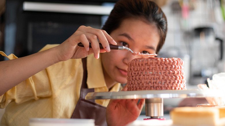 Woman frosting a cake with offset spatula