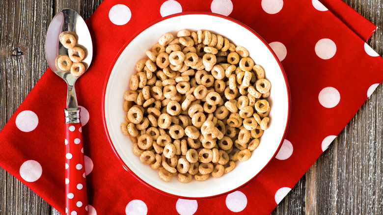 Bowl of cheerios next to spoon on table