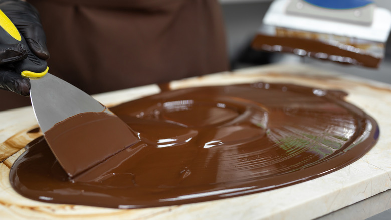 tempered chocolate being spread out with metal spatula