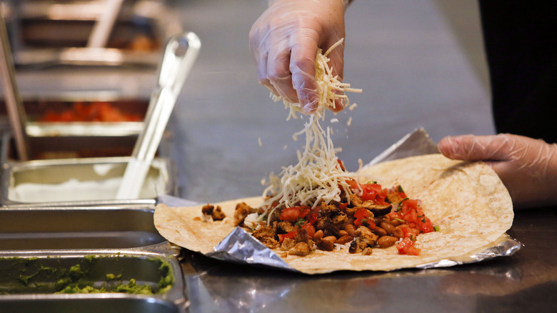 Chipotle employee adds cheese to burrito