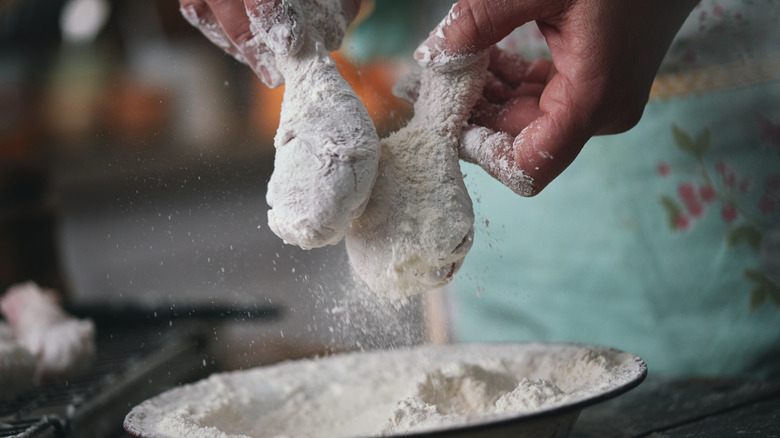 Person dredging chicken in flour