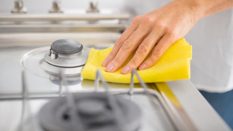 Yellow sponge cleaning a stove 