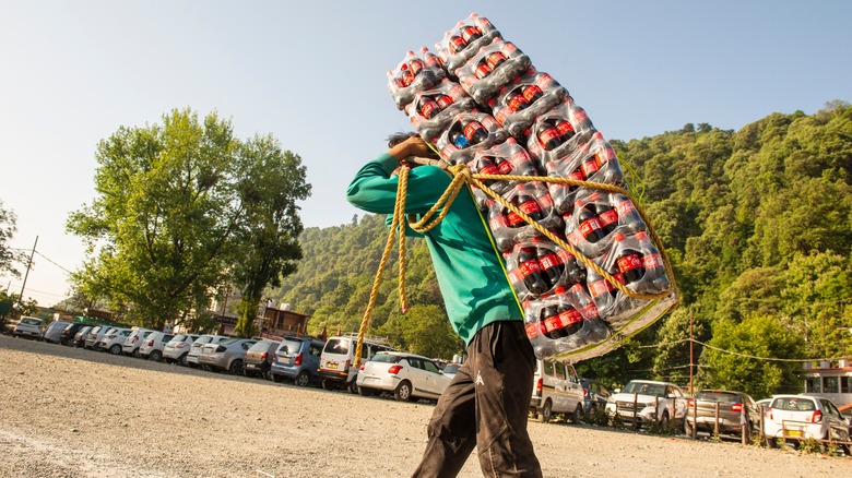 Man carrying cases of Coca-Cola in Indian village