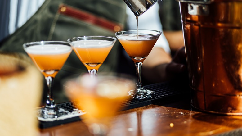 bartender pouring cocktail into glasses