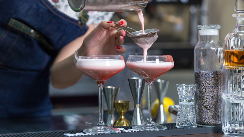 bartender pouring cocktails into glasses